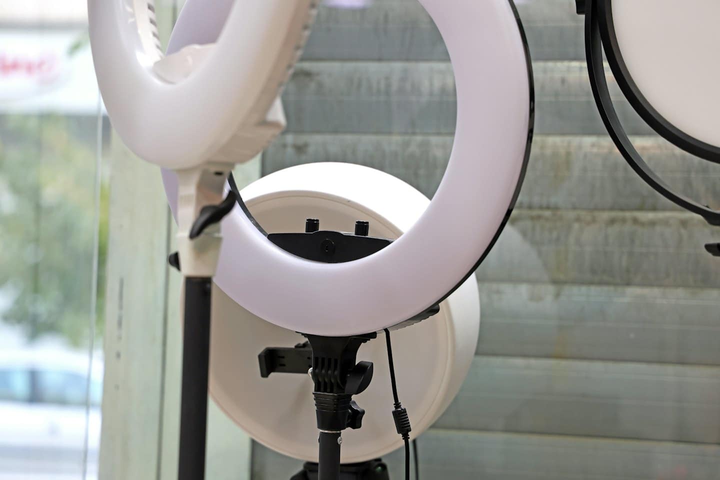 Professional studio ring lights and softbox on black stands indoors.