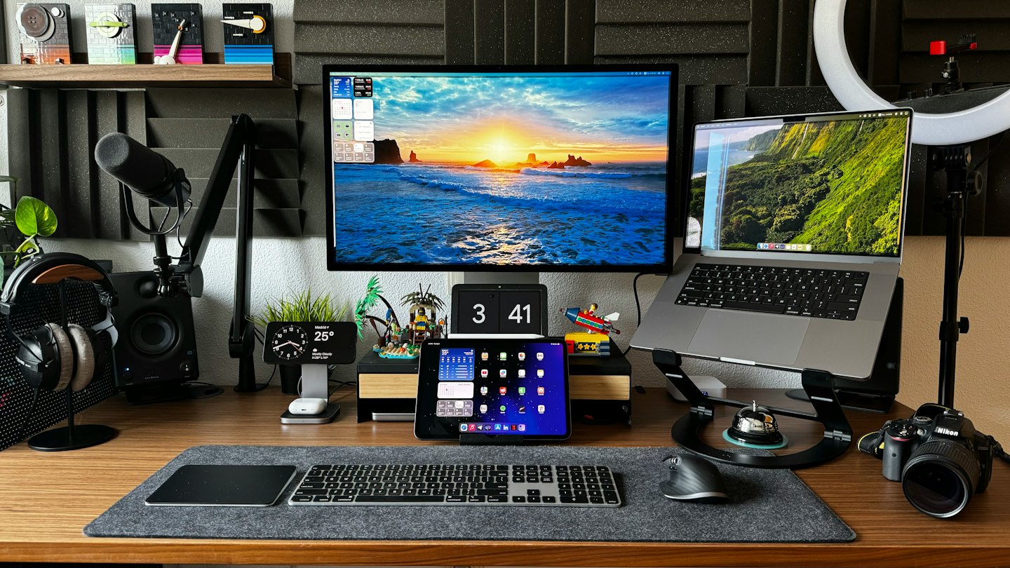 Modern home office desk with monitor, laptop, and microphone.