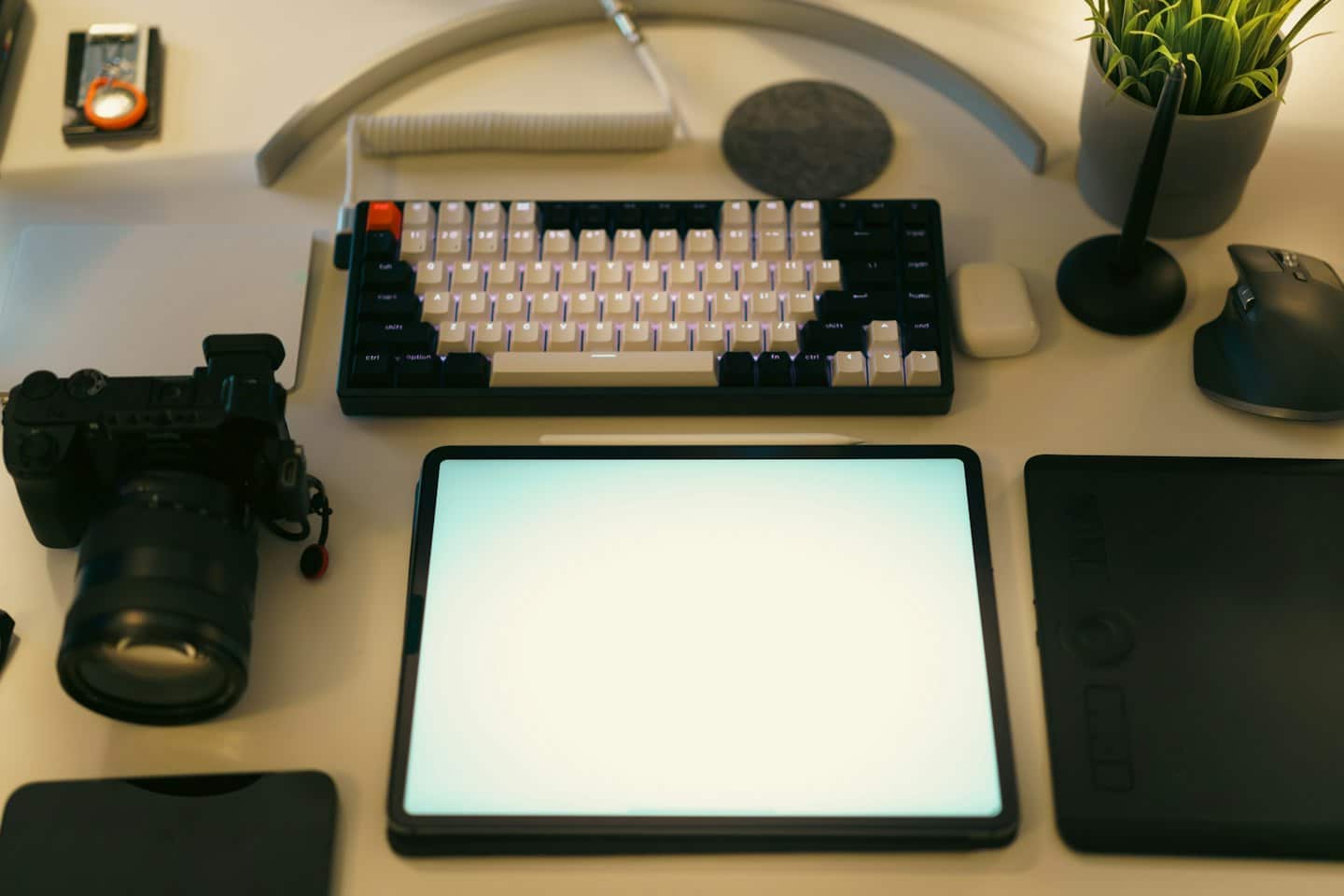 Modern desk with a keyboard, tablet, and tech gadgets.