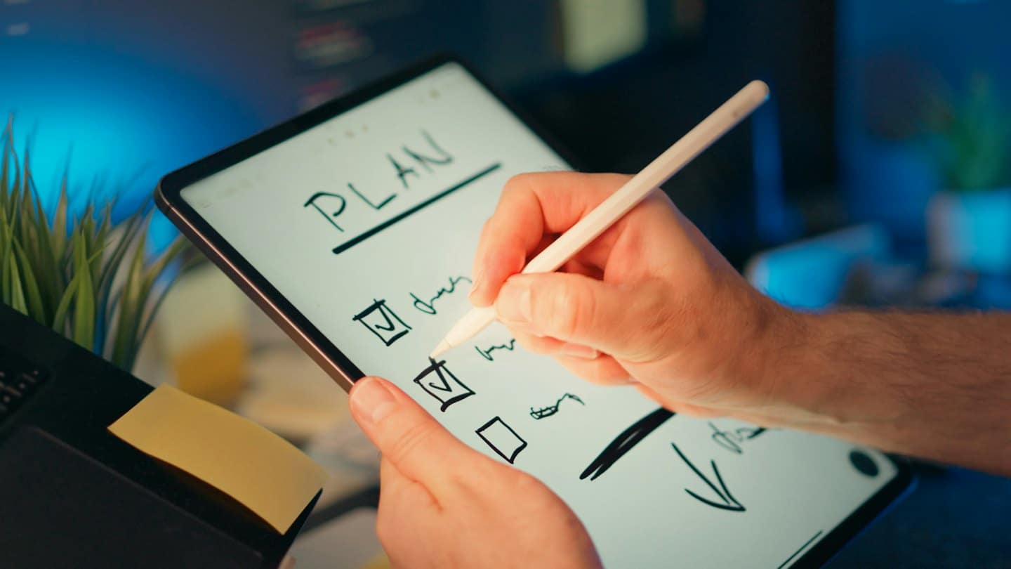 Hands using a digital pen on a tablet checklist.